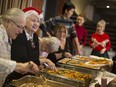 Barb Mailloux, left, and Bev Valliquette help serve up a Christmas Day tradition as they and other volunteers assist at Mezzo Ristorante's annual charity luncheon on Dec. 25, 2019.