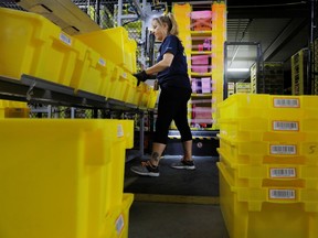 An Amazon employee works to stow items inside of shelves delivered by robots inside of an Amazon fulfillment center on Cyber Monday in Robbinsville, New Jersey, U.S., December 2, 2019.