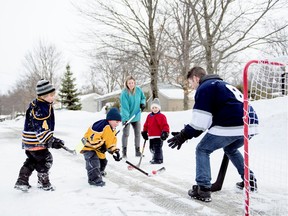 Kids play road hockey with a father on street in winter.