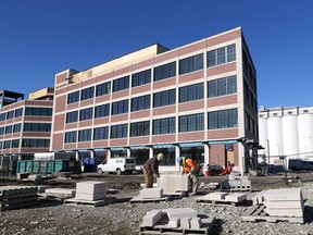 Stone masons Vince Zongaro, left, and Robert Incitti of Con-Tact Masonry prepare a slab of limestone at the Walker Power Building construction site Monday.  The historic building has been under an extensive rebuild at the corner of Devonshire Road and Riverside Drive East.  J.P. Wiser's Distillery (formerly Hiram Walker) grain silos are shown on right, behind the Power Building.