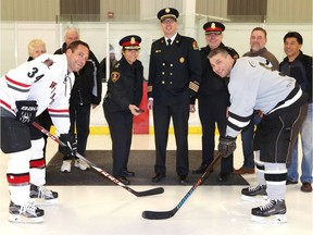 Team Windsor Fire captain Rocky Gelinas, left, and Team Windsor Police captain Shaun Ashton, take the honourary faceoff during the 25th annual 911 Hockey Tournament at Central Park Athletics Thursday.  The players were joined by Eleanor and Bernie Dame, left, Windsor Police Chief Pam Mizuno, Windsor Fire Deputy Chief James Waffle, Windsor Police Deputy Chief Brad Hill, Jim Lepine of Windsor Police and Wayne de Rozario, right of Windsor Fire Services.  The fundraising tournament supports the Kirk Dame Scholarship Fund and the Windsor Fire Peer Support Team.
