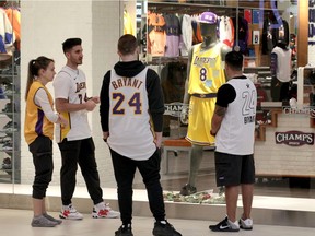 Elena Taparlvie, left, Erik Cirovski, Mike Chichkan and Sami Hakkani, right, gather around Kobe Bryant memorial display inside the window at Champs, Devonshire Mall Monday.  Cirovski and Hakkani, managers at Champs, brought in some of their own Kobe Bryant clothing to honour their hero. "He touched our generation," said Hakkani.  People passing by were placing sticky notes with personal messages on the window.