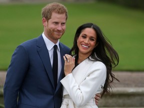 (FILES) In this file photo taken on on November 27, 2017, Britain's Prince Harry stands with his fiancee US actress Meghan Markle as she shows off her engagement ring whilst they pose for a photograph in the Sunken Garden at Kensington Palace in west London, following the announcement of their engagement. - Britain's Prince Harry and his wife Meghan will give up their titles and stop receiving public funds following their decision to give up front-line royal duties, Buckingham Palace said on January 18, 2020. "The Sussexes will not use their HRH titles as they are no longer working members of the Royal Family," the Palace said, adding that the couple have agreed to repay some past expenses.