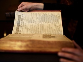 A worker poses with a first edition of the First Folio, the first collected edition of William Shakespeare's works, containing 36 plays, at Christie's auction house in London, Britain, April 19, 2016.
