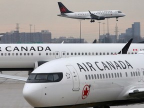 FILE PHOTO: Two Air Canada Boeing 737 MAX 8 aircrafts are seen on the ground as Air Canada Embraer aircraft flies in the background at Toronto Pearson International Airport in Toronto, Ontario, Canada, March 13, 2019.