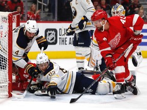Buffalo Sabres defenseman Brandon Montour (62) reaches for the puck in front of Detroit Red Wings centre Luke Glendening (41) in the second period at Little Caesars Arena in Detroit, Jan. 12, 2020.