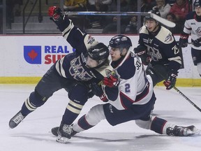 Windsor Spitfires' centre Tyler Angle, left, and Saginaw Spirit defenceman Ilya Solovyov get tangled up during Sunday's game at the WFCU Centre.