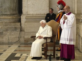 Emeritus Pope Benedict XVI sits near the Holy Door as Pope Francis leads a mass to mark opening of the Catholic Holy Year, or Jubilee, in St. Peter's Square, at the Vatican, in this Dec. 8, 2015, file photo.