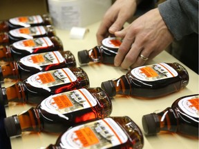 Adam Robson of Rolling Ridge Maple products applies a label to a bottle of maple syrup collected last spring in Ilderton, north of  London, Ont.