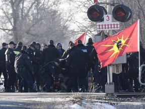 Ontario Provincial Police officers make an arrest at a rail blockade in Tyendinaga Mohawk Territory, near Belleville, Ont., on Monday Feb. 24, 2020, as they protest in solidarity with Wet'suwet'en Nation hereditary chiefs attempting to halt construction of a natural gas pipeline on their traditional territories. THE CANADIAN PRESS/Adrian Wyld