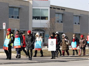 Striking teachers, union executives and supporters walk the picket line on the Campbell Avenue sidewalk in front of West Gate Public School Tuesday.