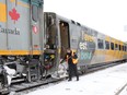 VIA Rail Canada train engineer Denis Eng, left, clears snow from the steps of a Toronto-bound train at Windsor's Walkerville Station on Feb. 13, 2020.
