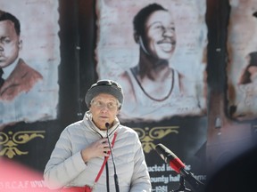 Pastor Carolyn Robinson-Dungy speaks about four of her relatives depicted on the Black History Murals in Sandwich Town during a ceremony in Paterson Park on Friday. Her smiling first cousin, athlete Fred Thomas, is pictured on the right.