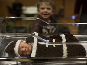 Sawyer Garant, 2, looks over his new born baby brother, Larkin Garant, son to Nick and Allie Garant, as he wears a crocheted football cocoon for Super Bowl Sunday on Feb. 2, 2020.