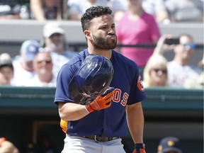 Houston Astros second baseman Jose Altuve recovers his helmet after it fell off on a swing during the first inning against the Detroit Tigers at Publix Field at Joker Marchant Stadium.