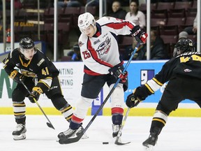 Windsor Spitfires' Kyle McDonald (25) tries to move the puck between two Sarnia Sting defenders during the 2019-20 season. The Spitfires will open the season at home against the Sting on Oct. 7 with a new starting time.