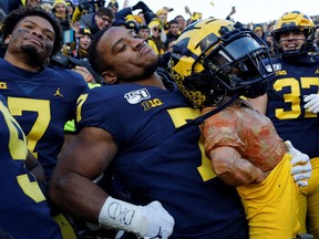 Michigan Wolverines wide receiver Tarik Black and linebacker Khaleke Hudson celebrate with the Paul Bunyan trophy after defeating the Michigan State Spartans at Michigan Stadium.