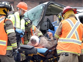 Tecumseh firefighters and Essex-Windsor EMS paramedics help an injured man rescued from a GMC Sierra pickup truck after it collided with a tractor-trailer on sout bound Walker Road near North Talbot on Monday. Two people were taken to hospital with non life-threatening injuries.