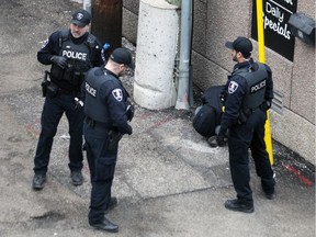 Windsor police officers stand by a man in apparent distress in a downtown alley the morning of Tuesday, March 3, 2020 while waiting for paramedics to arrive.
