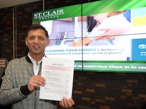 St. Clair College Vice President Amar Singh will be posting ways to self-isolate among other health conscious messages at main campus of St. Clair College Thursday. Behind Singh is a digital board with rotating messages about benefits of cleaning your hands.