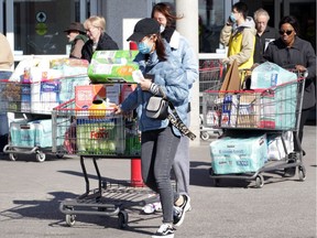 Crowds of shoppers load carts with toilet paper and other goods at the Costco on Walker Road in Windsor on March 13, 2020.