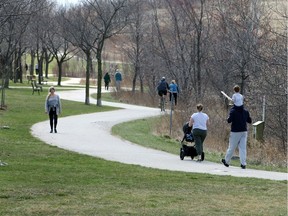 Windsor/Essex, Ontario. March 29, 2020. Area residents keep their distance while walking and riding on trails at East Riverside's Blue Heron Park Sunday.