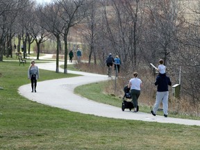 Windsor/Essex, Ontario. March 29, 2020. Area residents keep their distance while walking and riding on trails at East Riverside's Blue Heron Park Sunday.