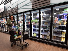 (FILES) In this file photo taken on March 19, 2020 Instacart employee Monica Ortega checks her cellphone for orders while picking up groceries from a supermarket for delivery in North Hollywood, California. - Grocery delivery service Instacart on March 23, 2020 announced plans to double the ranks of "shoppers" who fill orders in North America as people hunker down to reduce coronavirus risk. The San Francisco based firm said it wants to add another 300,000 "full-service shoppers" during the coming three months to meet soaring demand for grocery delivery or pick-up.