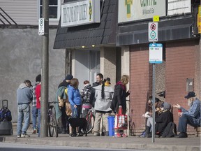 People congregate outside The Stone Soup Kitchen at the Street Help Homeless Shelter for meals being handed out through a window, Friday, March 20, 2020.