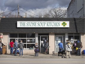 People congregate outside The Stone Soup Kitchen at the Street Help Homeless Shelter for meals being handed out through a window, Friday, March 20, 2020.