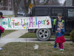 McKinley Nichols, 9, left, Elliot Nichols, 7, and Kate Nichols, 3, take part in a rally for the health-care staff at the Met campus of Windsor Regional Hospital while outside their home on Chilver Road in South Walkerville on March 27, 2020.