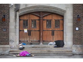 Two people sleep outside the front doors of The Downtown Mission, Monday, March 23, 2020, as the COVID-19 pandemic continues.