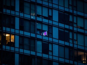 CBC journalist Andrew Chang is seen on a television in an upper floor condo, giving a report about the coronavirus, in Vancouver, on March 23, 2020.