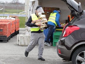 Workers and volunteers load up vehicles at the Unemployed Help Centre's new Drive Thru Food Bank Hub last week.