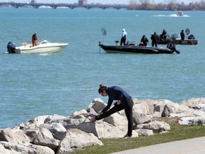 A jogger stretches along the Windsor riverfront near Glengarry Avenue as dozens of fishers roll with the Detroit River current for the annual walleye run Thursday.  Fishers were using jigs tipped with minnows while some used crank-baits.