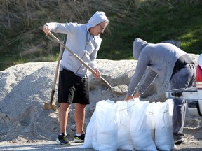 Riverside Drive resident Dino Mollica, left, gets help from his son Adamo Mollica filling sandbags at the city's depot at 9410 Little River Road Friday.