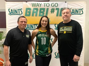 St. Clair assistant women's basketball coach Phil Milanis (at left), and head coach Andy Kiss (at right) welcome new recruit Gabrielle 'Gabi' Whiteye (centre).