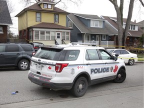 Windsor, Ontario. April13, 2020. A Windsor Police officer in a cruiser watches the area around 1375 Marentette Ave. (brick and yellow-sided home in centre) Monday. See story.