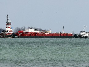 Tugs works with a barge that had run aground on Lake St. Clair near Peche Island on Tuesday.