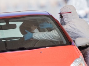 A woman at the wheel of her car undergoes a drive-through swabbing test for coronavirus on April 3, 2020 in Saint-Nazaire, western France, during the country's lockdown aimed at curbing the spread of the COVID-19 infection, caused by the novel coronavirus. (LOIC VENANCE/AFP via Getty Images)