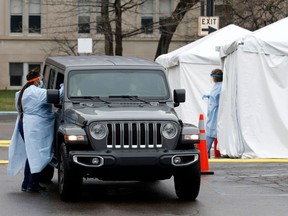 A person is tested for COVID-19 in the parking lot at Henry Ford Hospital in Detroit, Mich., on April 7, 2020. The Detroit News reported 734 employees at the Henry Ford Health System have tested positive for COVID-19.