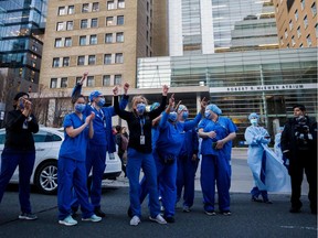 Healthcare workers cheer as Toronto first responders parade down hospital row in Toronto, Ontario, Canada, in a salute to healthcare workers on April 19, 2020, amid the novel coronavirus pandemic. - The worldwide death toll from the novel coronavirus pandemic rose to 164,016 on April 19, according to a tally from official sources compiled by AFP at 1900 GMT.