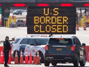 U.S. Customs officers speak with people in a car beside a sign saying that the U.S. border is closed at the US/Canada border in Lansdowne, Ontario. Canada's GDP plunged 9 per cent in March due to travel restrictions and temporary business closures to fight the coronavirus pandemic, said Statistics Canada.