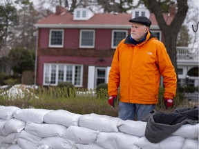 Don Wilson, a power of attorney for an elderly lady that lives on Riverside Drive East, and whose house is being threatened by flooding, stands behind a wall of sandbags, Thursday, April 16, 2020.