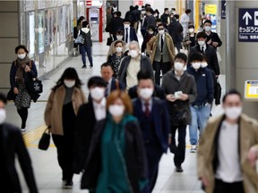 Passengers wearing protective face masks, following an outbreak of the coronavirus disease (COVID-19), walk to work the day before a state of emergency is expected to be imposed at a station in Tokyo, Japan, April 7, 2020.