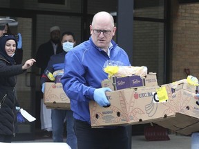 Windsor Mayor Drew Dilkens is seen in this April 10 file photo carrying a load of food during the  launch of a volunteer food hamper delivery service organized by the Windsor Islamic Association.