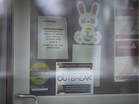 Signs warning of an outbreak are shown April 14, 2020, posted on the front door to Country Village Homes, a long-term care facility in Woodslee.