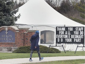 In this April 22, 2020, a woman walks by the Heron Terrace long-term care home in Tecumseh with a pandemic message of thanks to the staff and advice for the public.