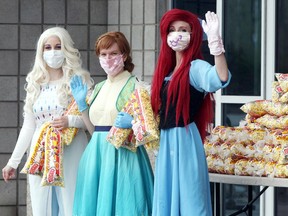 Sylvia Ward, left, Meagan Marcoux and Rachel Gray wave to motorists during a free popcorn event at Imagine Cinemas Lakeshore Friday May 22, 2020.