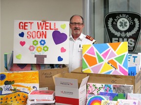 Art to "brighten walls and brighten spirits." Essex-Windsor EMS Chief Bruce Krauter, shown at EMS headquarters on  Friday, May 15, 2020, sorts through some of the more than 2,500 inspirational pieces of art received from local children and being distributed to area hospitals and long-term care homes in honour of National Nursing Week.